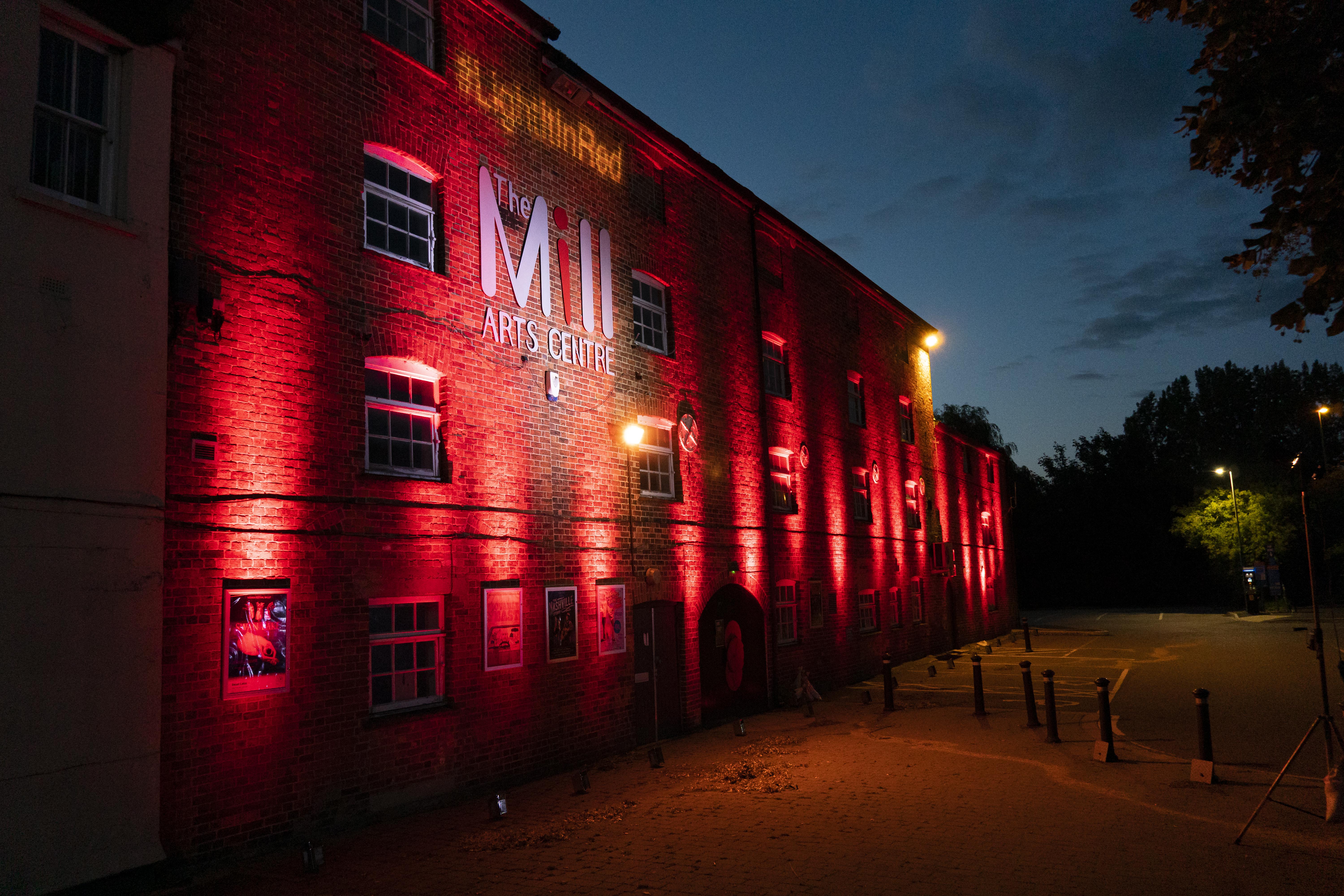 Exterior of The Mill building lit up in red