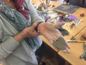 Person holding a handmade clay heart in their hand