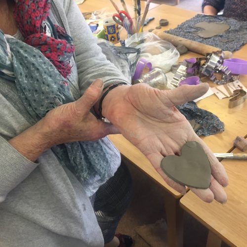 Person holding a handmade clay heart in their hand