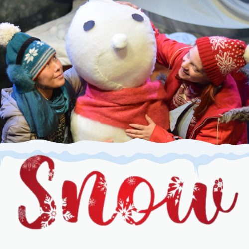 Actors in woolly hats and coats with a giant snowman