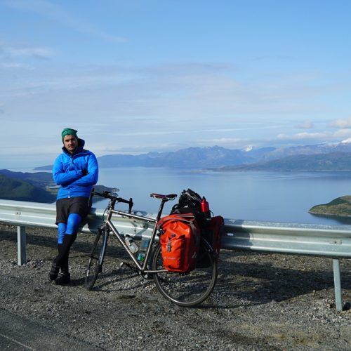 Simon Parker stands next to his bike in front of a mountain vista