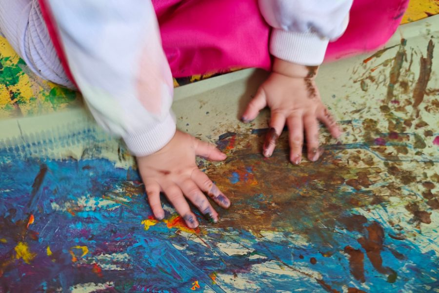 Childs using their hands painting messily on the floor